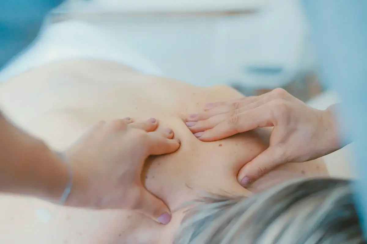 Physiotherapist treating a patient's back and shoulder during a session