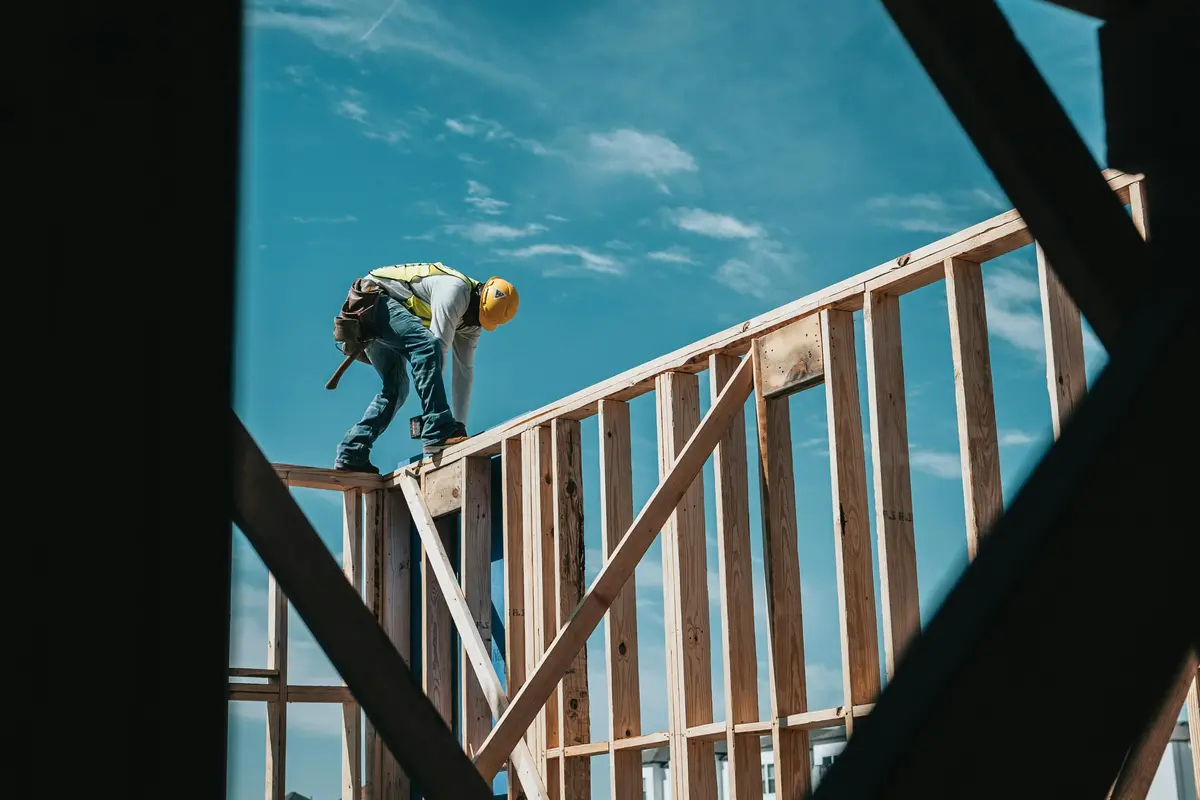 A construction worker in a hard hat on a building frame, the kind of active project that helps a construction company win more clients