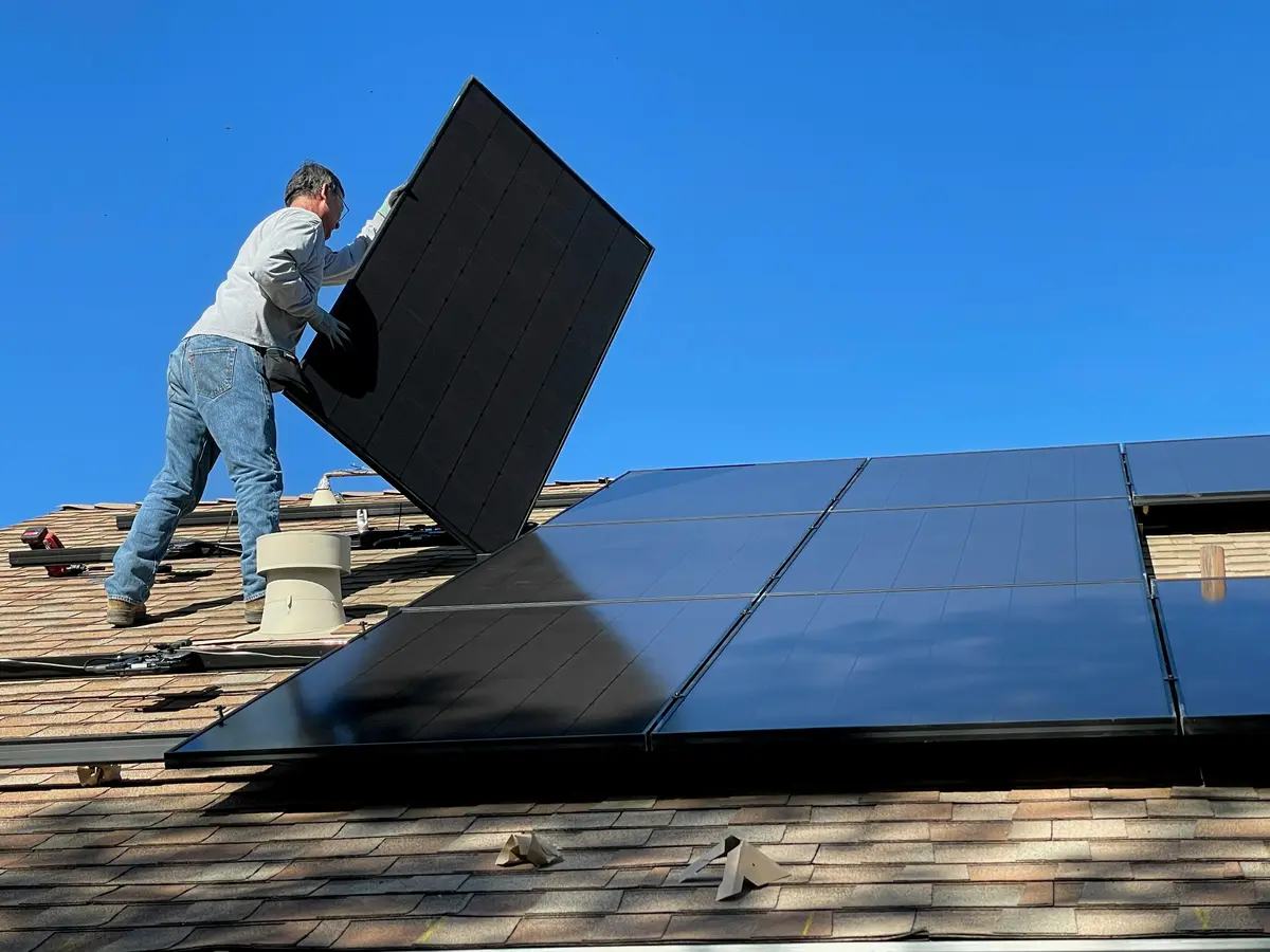A worker installing solar panels on a roof, the kind of registered, documented electrical work that builds a steady client base