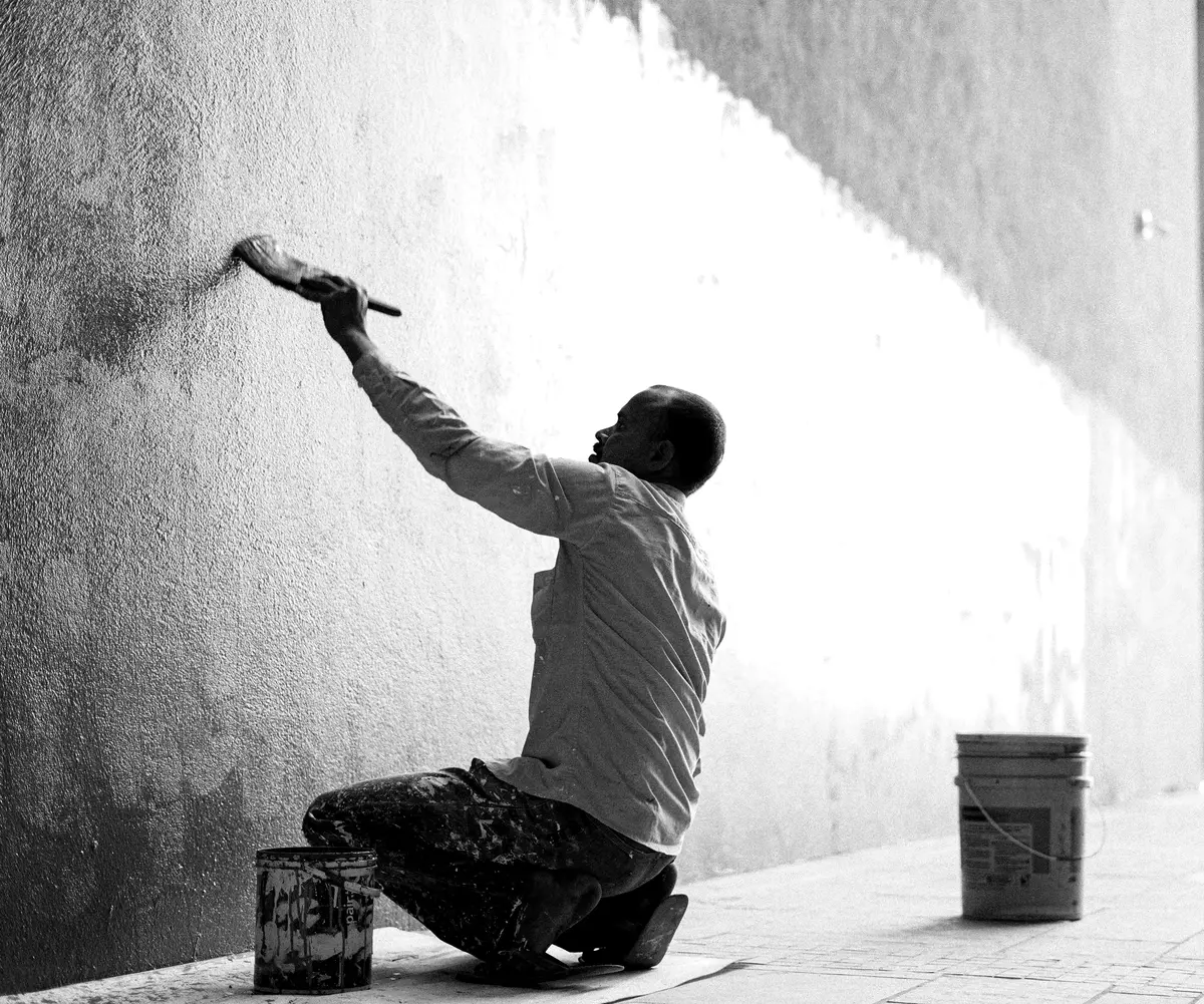 A painter using a roller to paint an interior wall, the kind of tidy, professional work that helps a painting contractor win more jobs