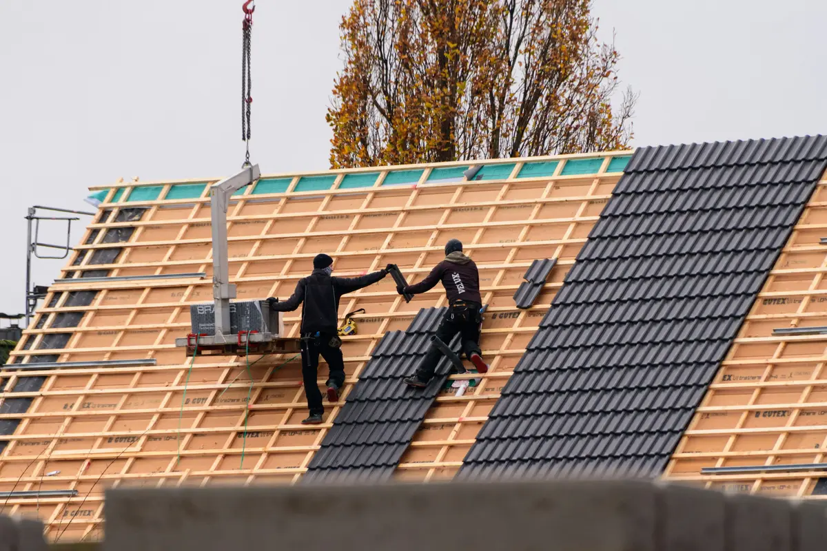 Roofing workers installing tiles on a new building, the kind of careful, documented work that helps a roofing contractor win more work